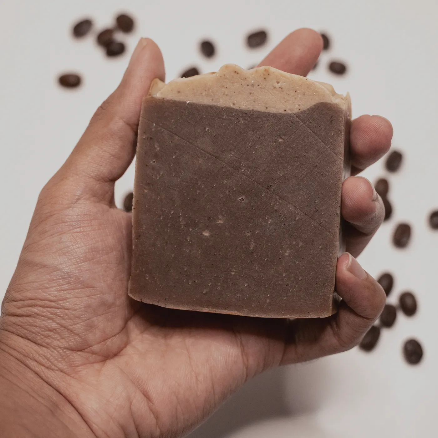 A bar of Espresso coffee soap held in a hand, showing its size