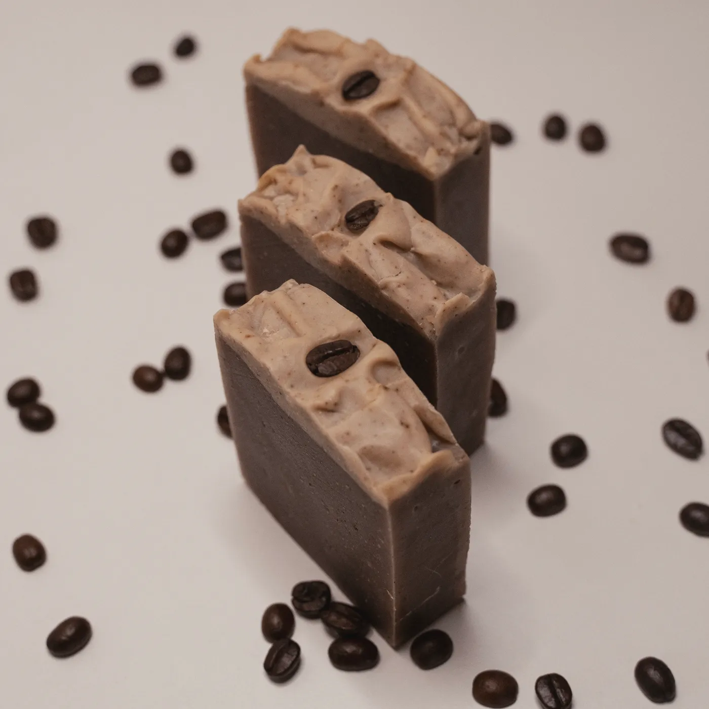 Three bars of Espresso soap standing in a row among coffee beans