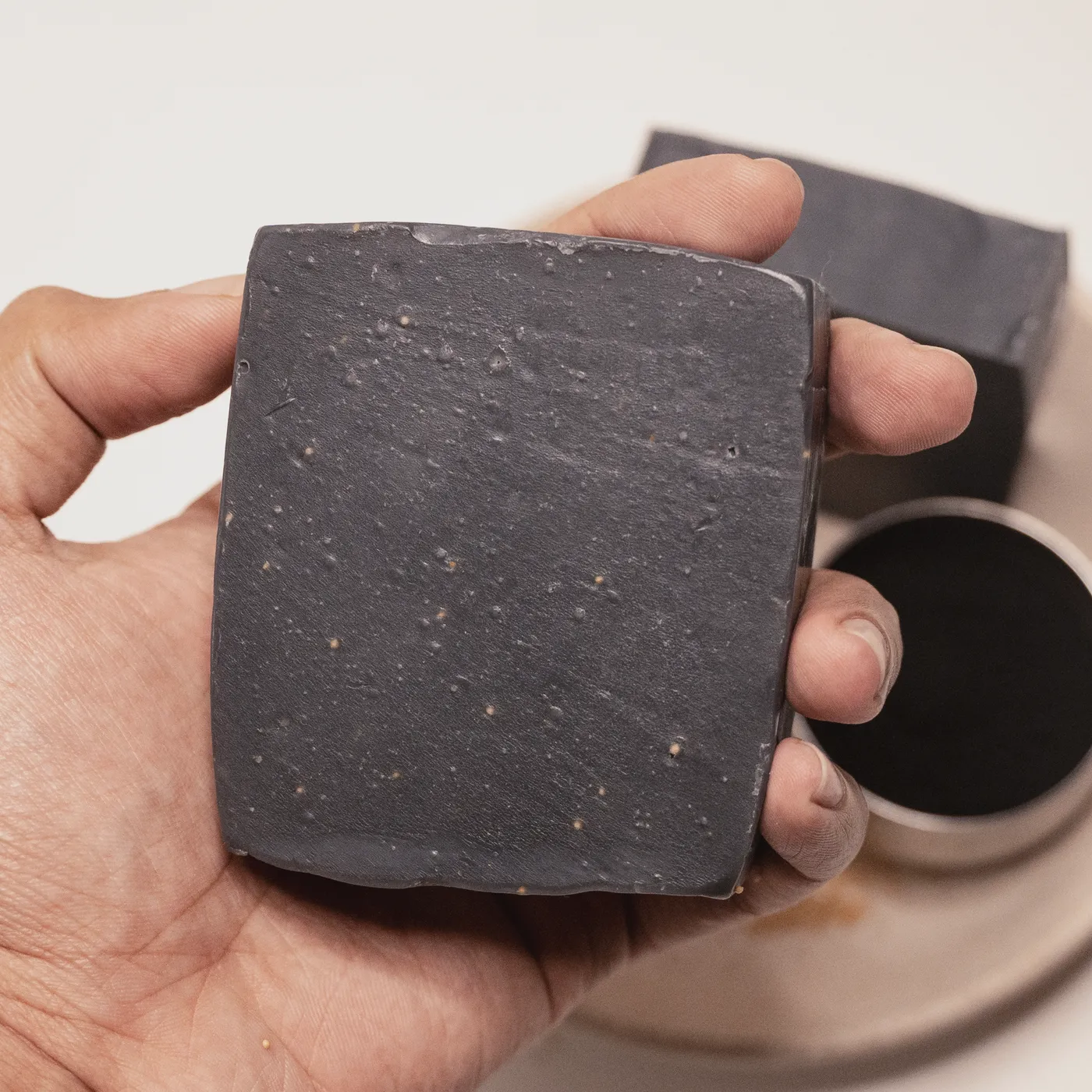A bar of Noir charcoal soap held in a hand