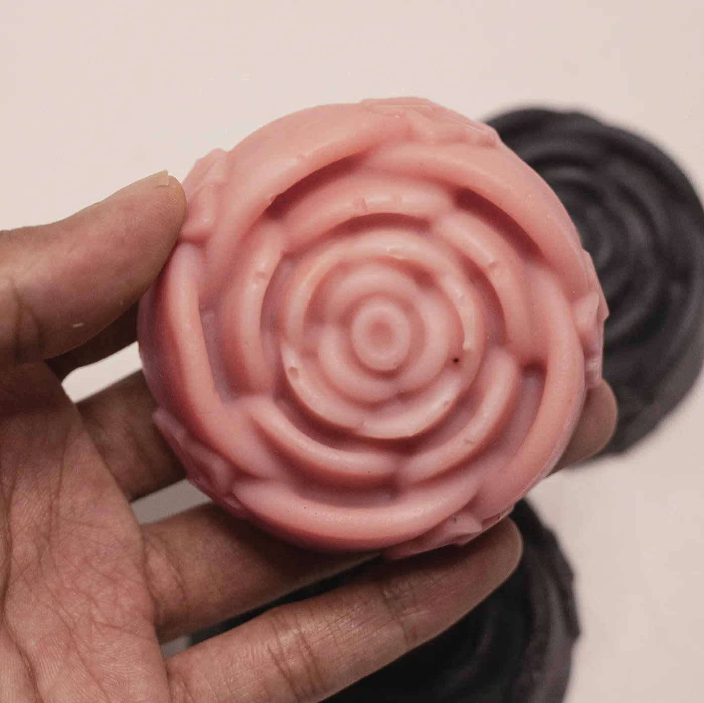 A pink rose-moulded soap held in a hand