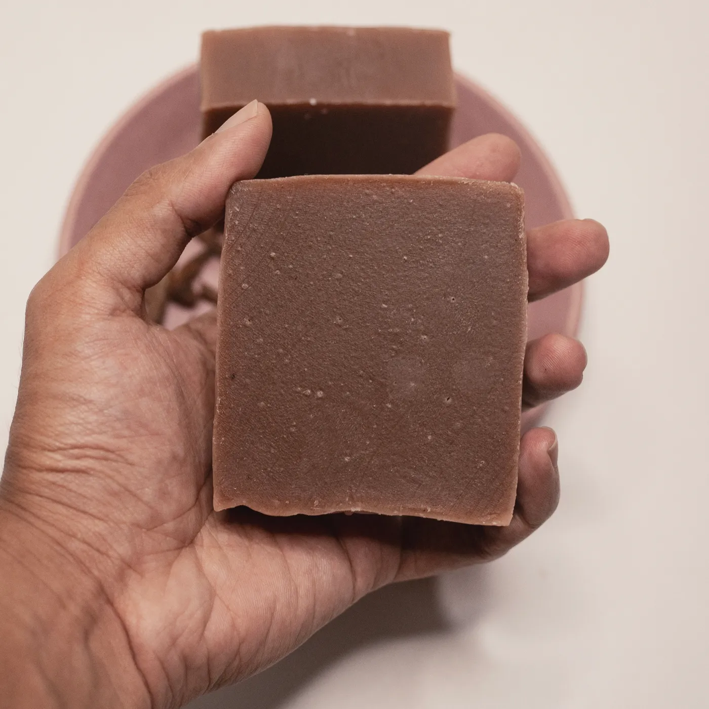 A bar of Ruby Root soap held in a hand